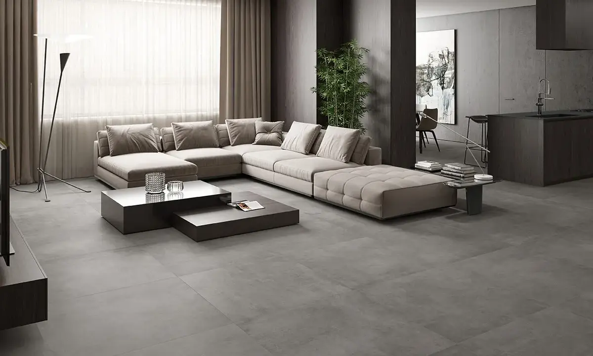 Elegante salón con sofá modular beige y mesas de centro oscuras sobre un suelo de hormigón pulido, mostrando diferentes tipos de suelo.