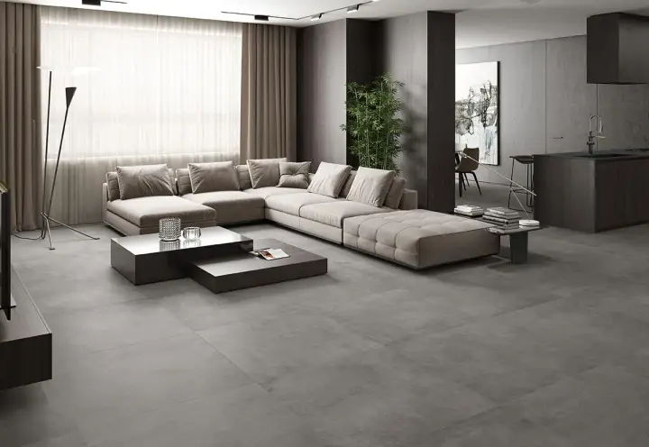Elegante salón con sofá modular beige y mesas de centro oscuras sobre un suelo de hormigón pulido, mostrando diferentes tipos de suelo.